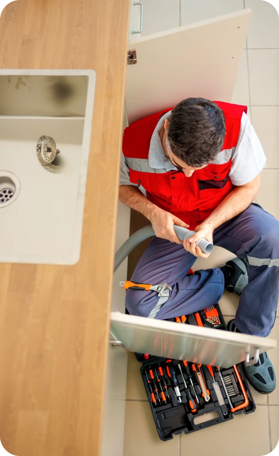 Plumber fixing kitchen sink pipe